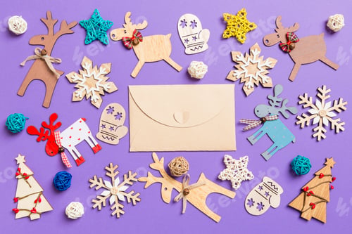 Preview: Festive decorations and toys on purple background. Top view of craft envelope.
