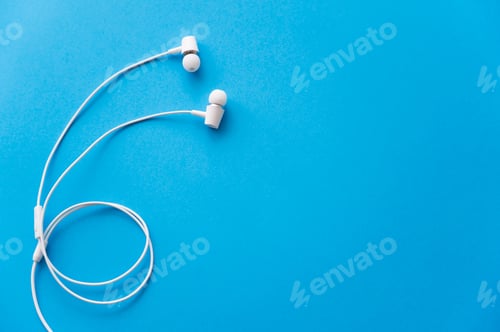 Preview: top view of white wired earphones on blue