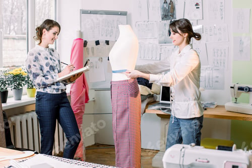 Preview: Two female tailors or seamstress taking mannequin measurements