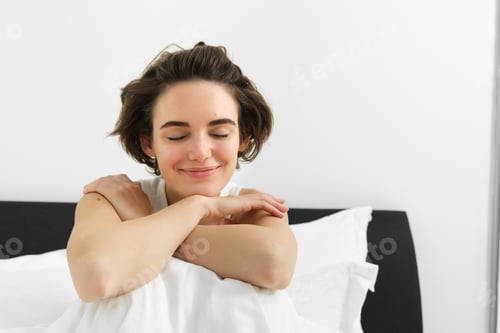 Preview: Portrait of smiling, happy young woman with sensual face, relaxing in bed, waking up, sitting with