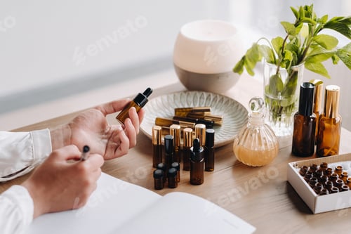 Preview: Close-up of female hands holding a bottle of essential oil and writing an entry in a notebook