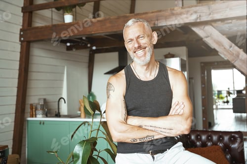 Preview: Portrait of a handsome cheerful caucasian mature man keeping arms crossed, smiling at camera while