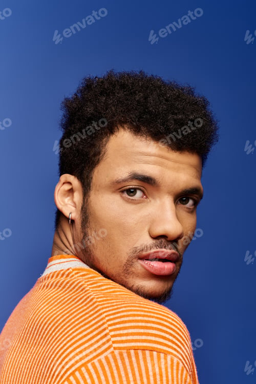 Preview: Handsome man with striking features posing against a vibrant blue background