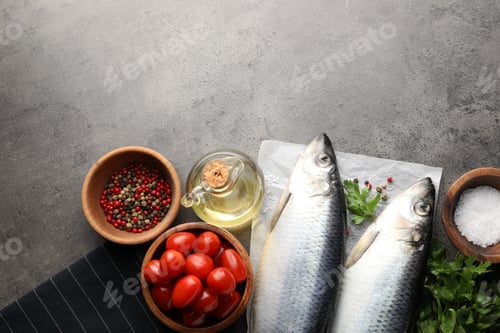 Preview: Salted herrings, spices and tomatoes on grey table, flat lay. Space for text