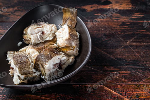 Preview: Roasted hake white fish in a plate. Dark wooden background. Top view. Copy space