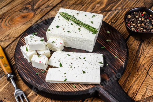 Preview: Cut cheese feta with rosemary on a wooden cutting board. wooden background. Top view