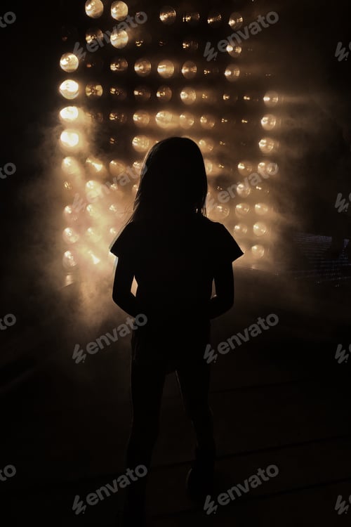 Preview: Silhouette of a girl standing in front of a light installation in the night