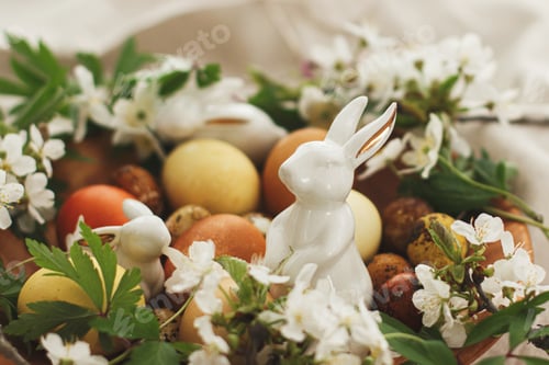 Preview: Happy Easter! Modern easter eggs with spring flowers and bunny in wooden bowl on rustic linen