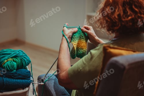 Preview: Close up of the hands of a senior woman knitting at home.