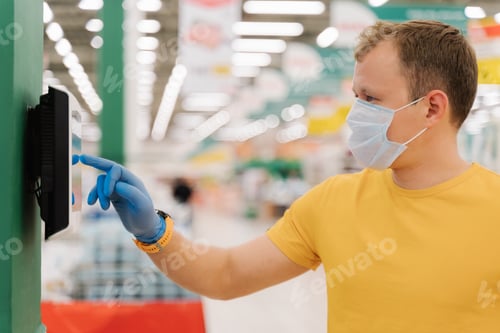 Preview: man types on touch screen of self checkout, wears protective rubber blue gloves