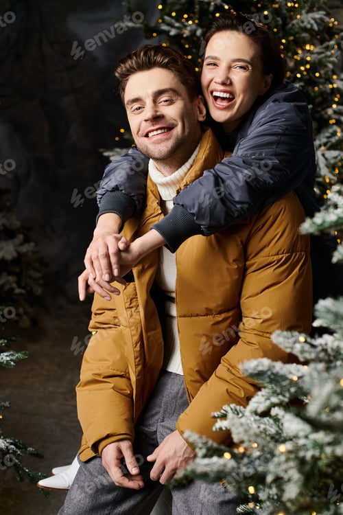 Preview: A joyful couple in warm jackets celebrates Christmas near snowy pine trees