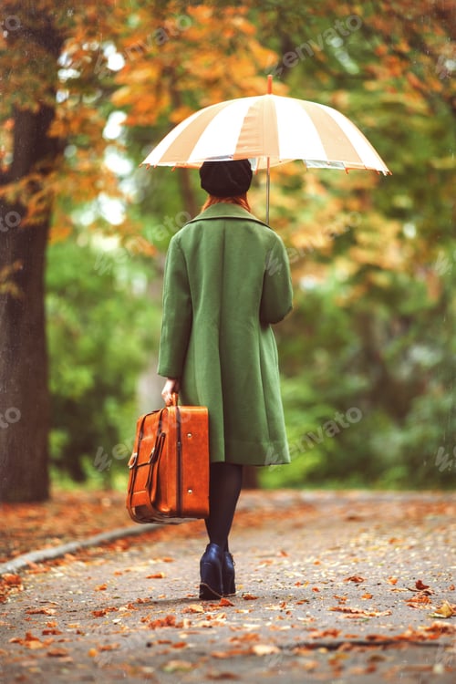 Preview: Redhead girl with suitcase at autumn outdoor.