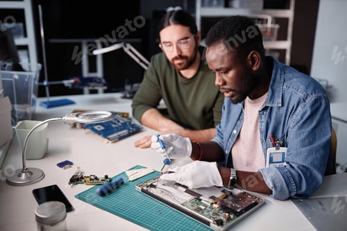 Preview: Two people fixing computer in tech repair