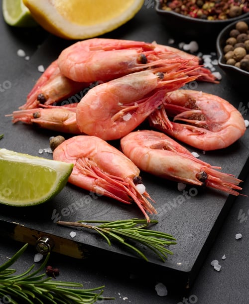 Preview: Boiled shrimp on a board, lemon slices, spices on a black background