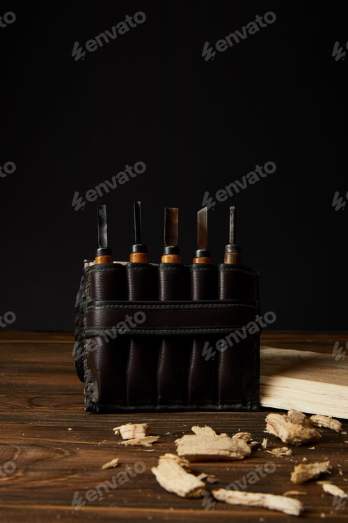 Preview: closeup shot of chisels in leather case and wooden pieces on table