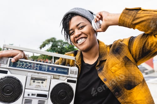 Preview: Happy African girl having fun listening to music with headphones and vintage boombox stereo