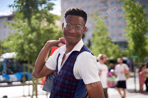 Preview: Smiling young african american man carrying shopping bags and looking at camera