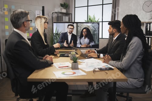Preview: Focused business people in conference room, looking at a screen, having video conference