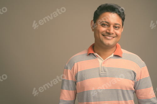 Preview: Young Indian man against gray background