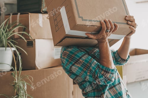 Preview: One woman lifting up heavy cardboard box during relocation moving house activity alone mortgage
