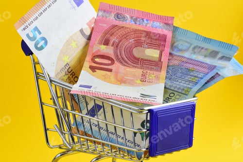 Preview: Shopping cart with euro banknotes isolated on yellow background. Concept of price increase