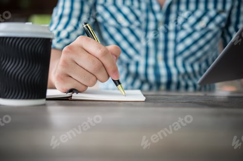 Preview: Close up of man hand writing in notebook with pen.