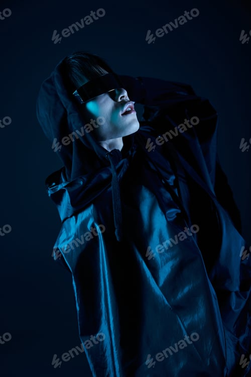 Preview: Stylish young man showcases modern fashion against a dark and moody backdrop at an urban venue