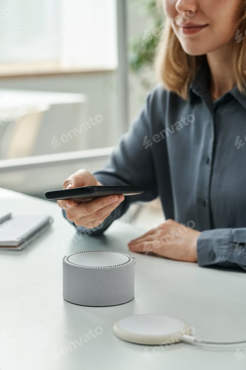 Preview: Woman connecting smartphone with smart speaker