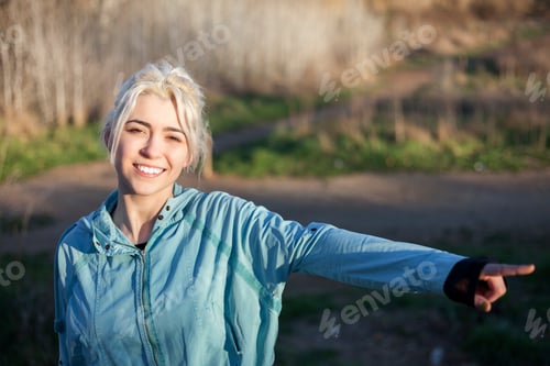Preview: smiling sporty woman watching and pointing far away