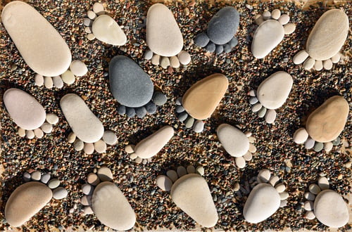 Preview: Pebble stones arranged like footprints on the beach