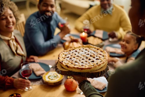 Preview: Close up of black woman serving Thanksgiving pie during family meal.