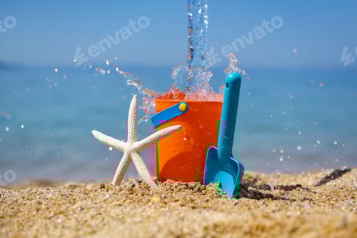 Preview: Bright plastic сhildren's beach toys and a starfish on sand near sea. Summer vacation concept