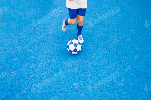 Preview: Little unrecognizable boy playing soccer of blue background