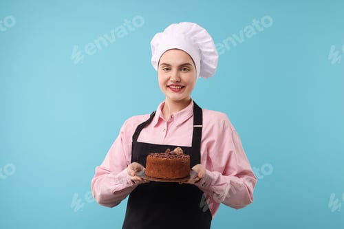 Preview: Confectioner with delicious chocolate cake on light blue background