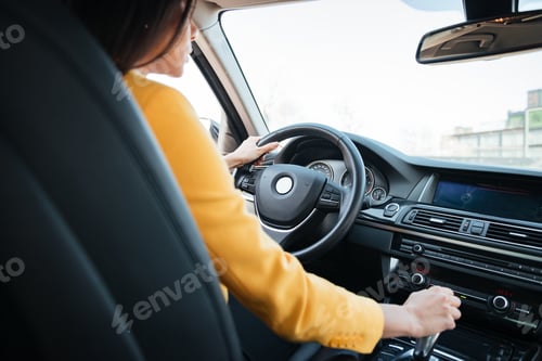 Preview: Back view of attractive young woman looking on the road while driving a car