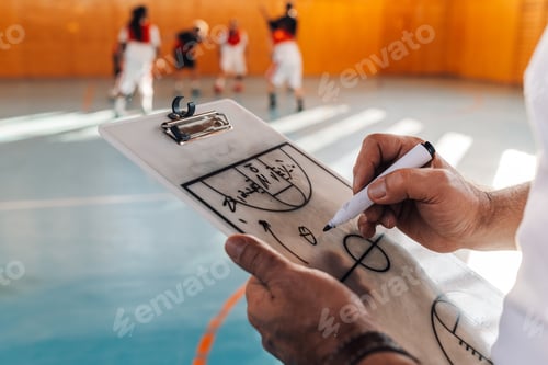 Preview: Elderly male basketball coach drawing his strategy on a coach clipboard