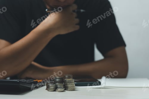 Preview: Businessman put coin stack money and many bank note in office.