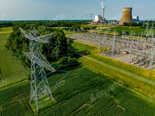 Preview: Aerial view of power lines leading to an industrial plant amidst green fields