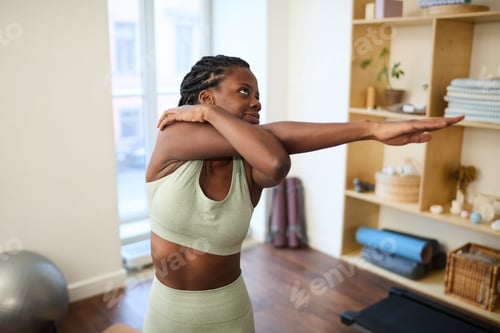 Preview: Exercising Woman Stretching Arm in Modern Fitness Studio