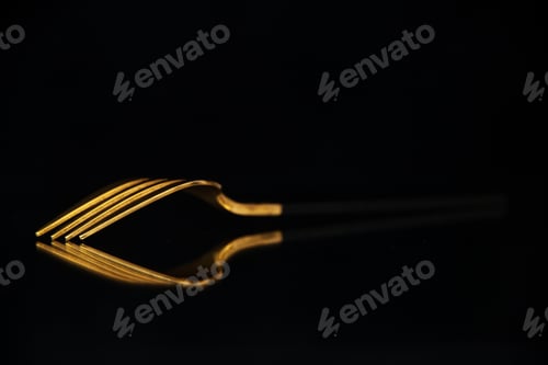 Preview: Elegant shiny golden fork put upside down on black background with free space in side view
