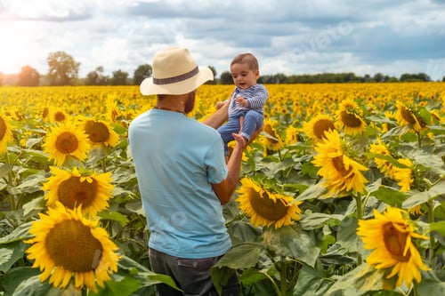 Preview: Portrait of a Caucasian father and his baby having fun in a field of sunflowers
