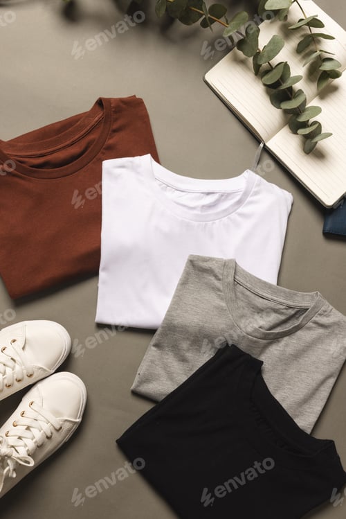 Preview: Multi coloured t shirts, shoes and notebook with copy space on grey floor background