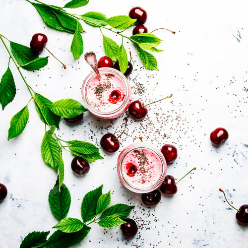 Preview: Pink cherry milkshake with berry and chia seeds, white stone background, top view