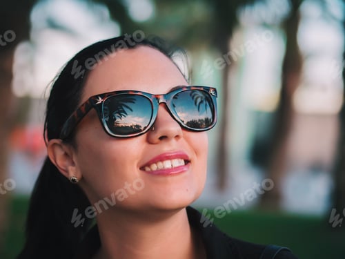 Preview: Happy woman in sunglasses with palms reflection