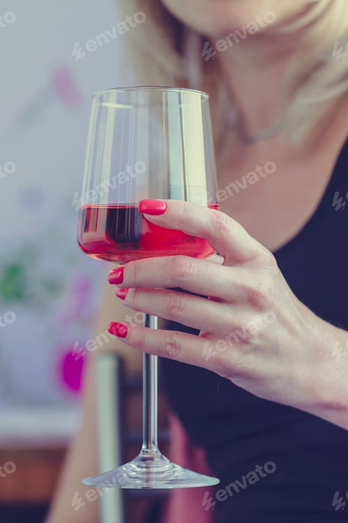 Preview: Female hand holding glass of rose wine, closeup