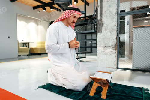 Preview: Young arab muslim man reading the holy Quran in the office
