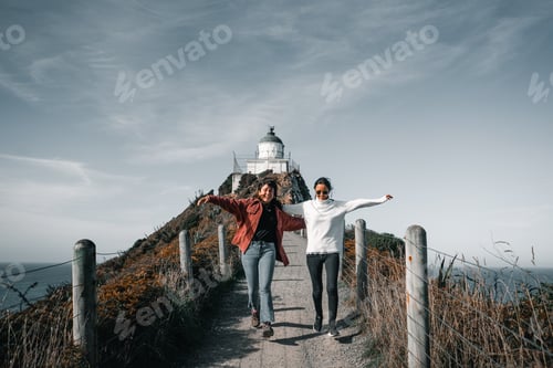 Preview: two caucasian girls running down the dirt road leading to the lighthouse on top of the big rock near