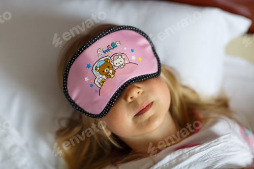 Preview: Little Caucasian girl with blonde hair wearing blindfold when sleeping in bed