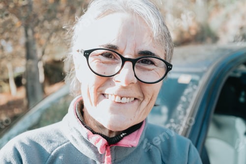 Preview: Portrait of a happy smiling senior woman outside car learning to drive a car.