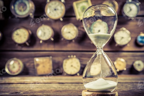 Preview: Aged hourglass on the background of clocks